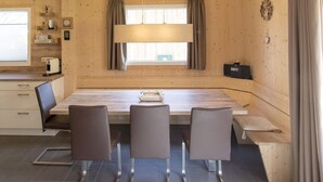 A cozy wooden interior with a dining table, chairs, a kitchen area, and a window with curtains. - Spacious Chalet With Infrared Sauna (Sankt Georgen am Kreischberg)