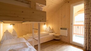 A wooden cabin room with bunk beds, a sofa, and a window with curtains. - Spacious Chalet With Infrared Sauna (Sankt Georgen am Kreischberg)