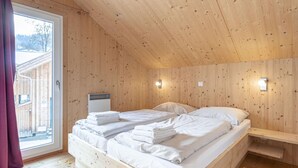 Een houten kamer met een bed, een verwarming en een raam met gordijnen.