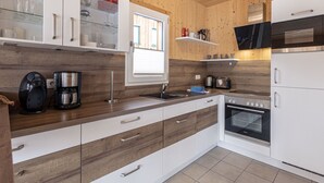 Een moderne keuken met houten kastjes, een inbouwoven en een koffiezetapparaat.