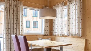 Een houten cabin met een zithoek met een bank, een tafel en gordijnen met een patroon.