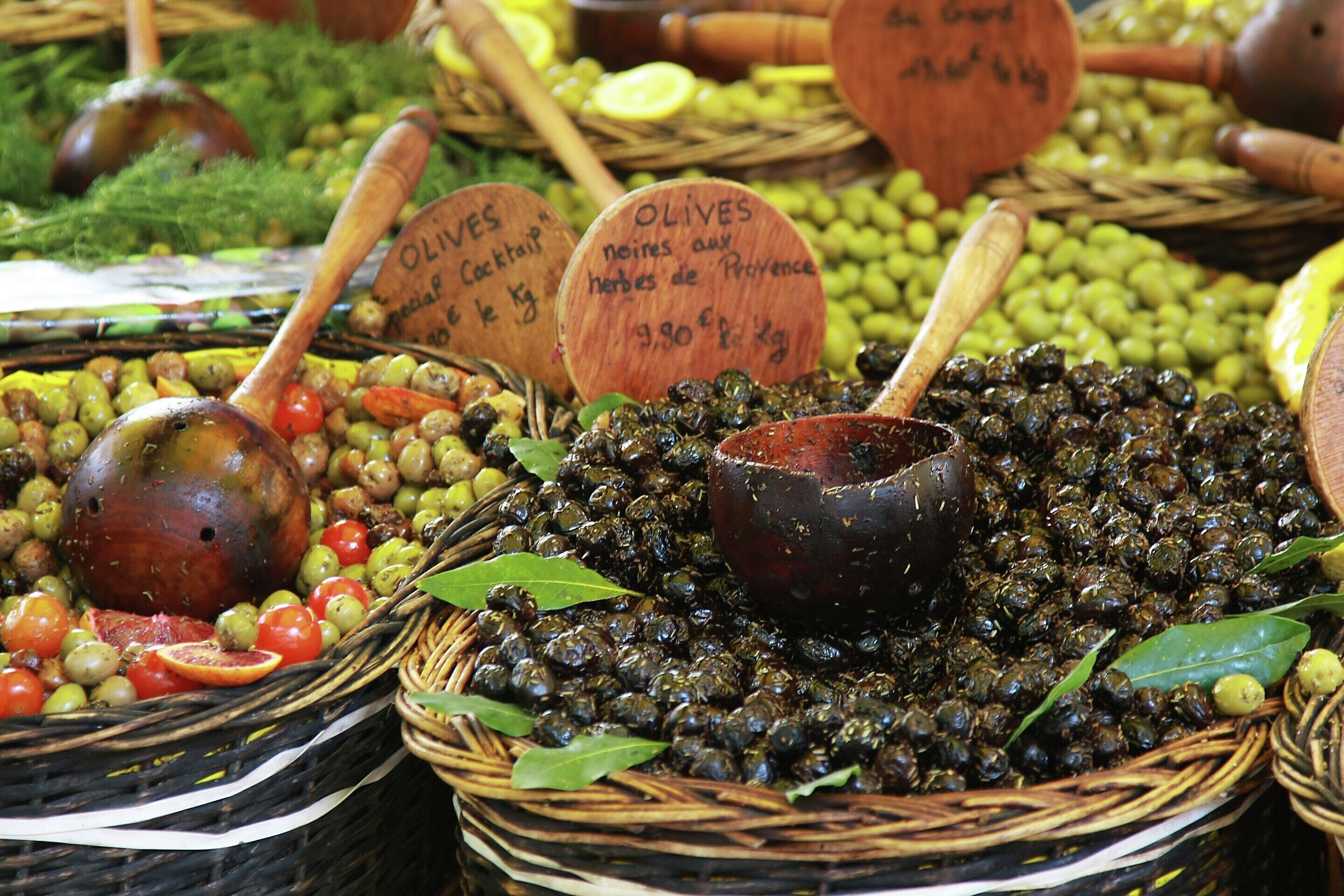 Cestas de aceitunas y alcaparras con cucharones de madera y etiquetas.