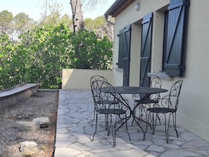 A patio with a stone floor, a table, and four chairs.