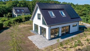 Una casa moderna a due piani con tetto spiovente e ampie finestre.