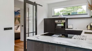 Una cucina moderna con un'ampia finestra, mobili scuri e un piano di lavoro in marmo.