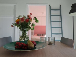 A dining table with a vase of flowers, a plate with fruit, and a ladder against the wall. - Pleasant House Directly Behind the Dunes of the Netherlands' Largest Southern Beach (Koudekerke)