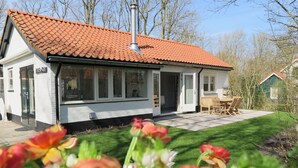 A house with a tiled roof, a chimney, and a patio with a table and chairs.