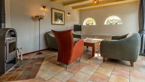Un salon chaleureux avec une cheminée, des sièges confortables et une grande fenêtre offrant une belle vue.