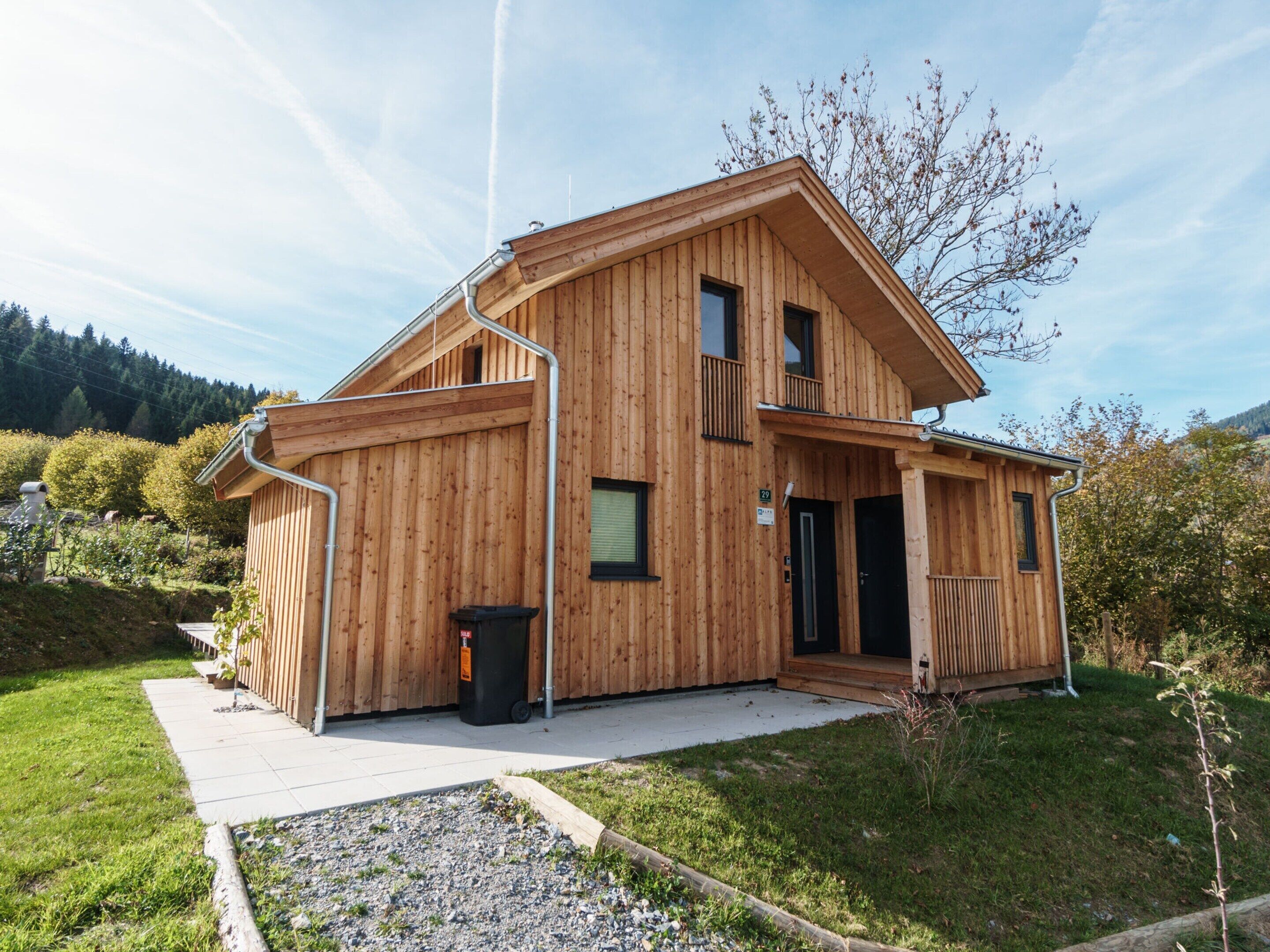 A two-story wooden house with a balcony, a front door, and a small porch.