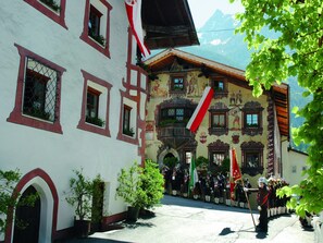 A traditional building with a white facade and red trim, featuring a balcony and a mural. - Apartment in Oetz Near Ski Lift (Oetz)