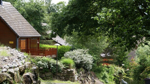 A rural road leading to a wooden house with a stone wall and a wooden fence. - Chalet du Lac - Nature Escape (Beaulieu)