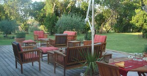 A wooden deck with outdoor furniture, including chairs and a table, surrounded by greenery. - Villa in Poggio-mezzana Near the Sea (Poggio-Mezzana)