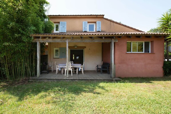 A two-story house with a covered patio, a dining table, and chairs. - Villa in Poggio-mezzana by the Beach (Poggio-Mezzana)
