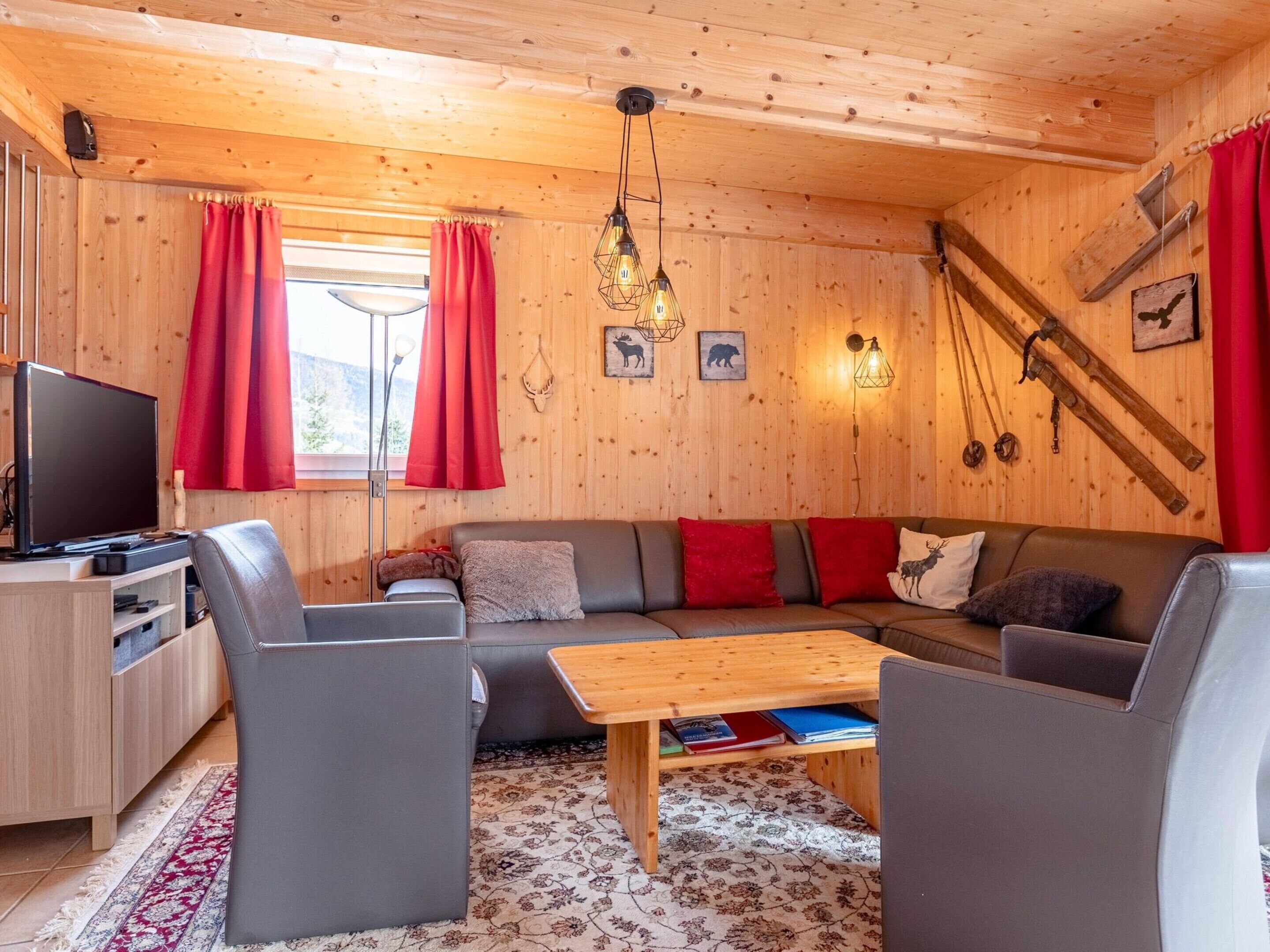 A cozy cabin interior with a wooden interior, a sofa set, a television, and a dining table.