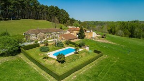 Ein weitläufiges Anwesen mit Swimmingpool, Steingebäuden und einem gepflegten Rasen.
