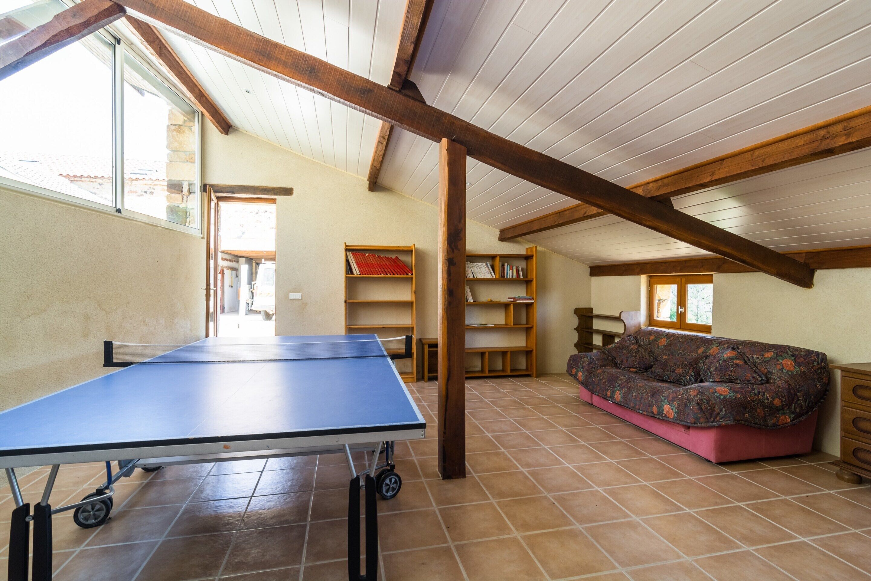 Une pièce avec une table de ping-pong, des étagères en bois, un canapé et un sol carrelé.