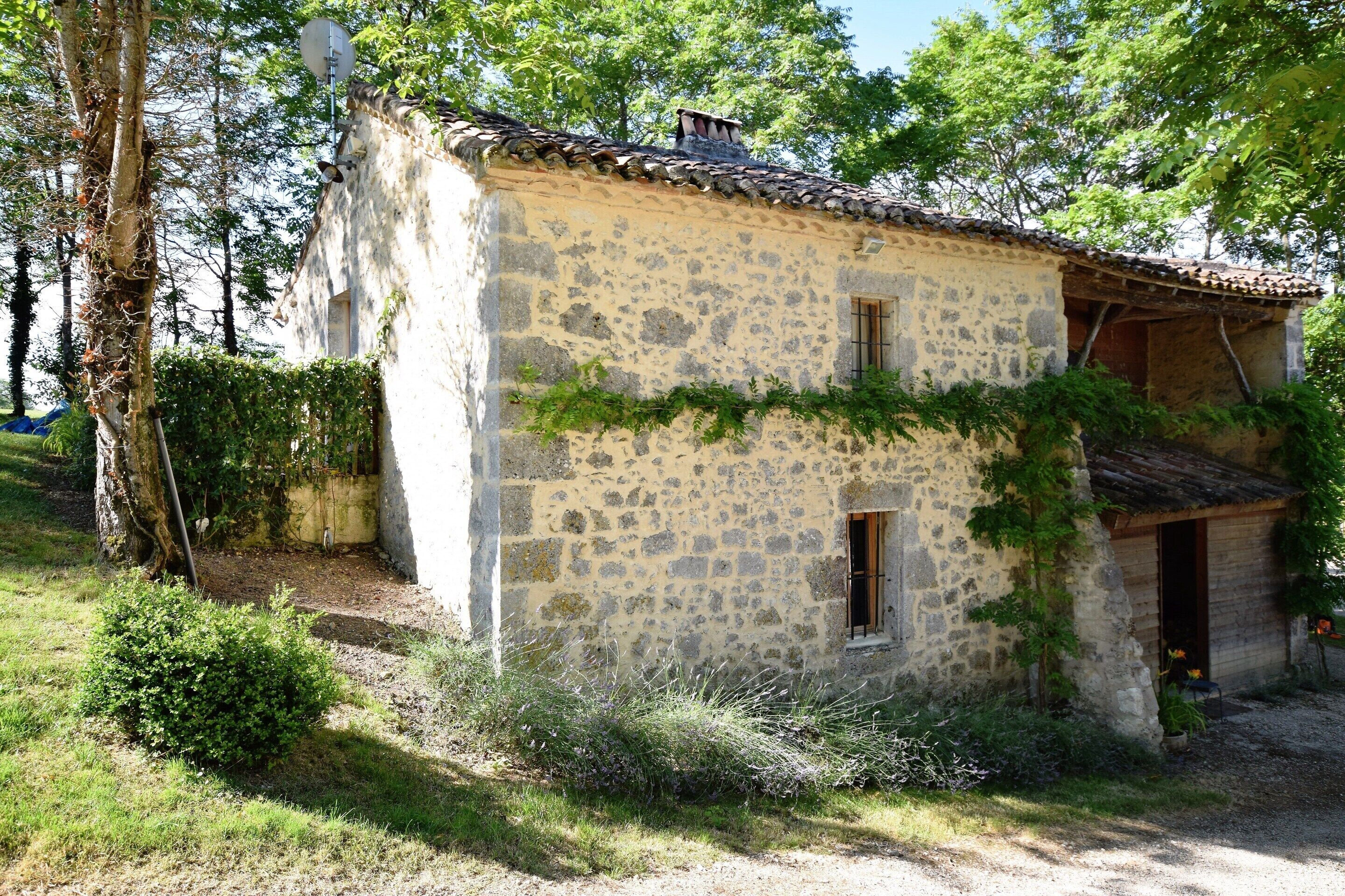 Une maison de campagne en pierre, avec un toit en tuiles, une petite fenêtre et une porte.