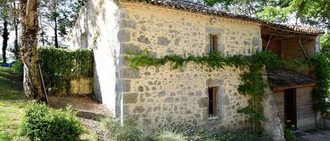 Une maison de campagne en pierre, avec un toit en tuiles, une petite fenêtre et une porte.