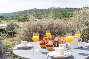 Een ontbijttafel buiten, met uitzicht op een glooiend landschap.