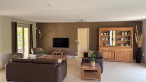 Un salón con sofá, mesa de centro, televisor y mueble.