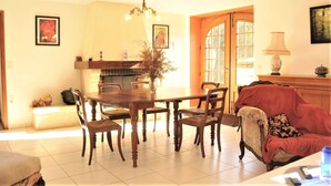 A dining area with a wooden table and chairs, a chandelier, a fireplace, and a sofa. - Historic Dordogne Escape (Loubejac)