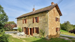 A stone house with a tiled roof, a chimney, and a small garden with a table and chairs. - Historic Dordogne Escape (Loubejac)