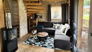 A cozy living room with a fireplace, a sofa, a coffee table, and a TV. - Appealing Chalet Near ski Slope (Sankt Georgen am Kreischberg)