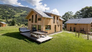 A wooden cabin with a deck and outdoor seating, surrounded by a grassy landscape and hills. - Appealing Chalet Near ski Slope (Sankt Georgen am Kreischberg)