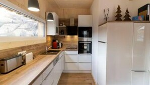 A compact kitchen with wooden cabinets, a built-in oven, and a window overlooking a snowy landscape. - Appealing Chalet Near ski Slope (Sankt Georgen am Kreischberg)