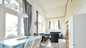Una habitación luminosa y bien iluminada con una mesa de comedor, sillas, sofá y un refrigerador.