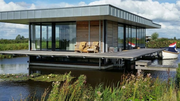 A modern houseboat with a flat roof, large windows, and a deck with chairs. - House Boat in Goengahuizen With Sauna (Goengahuizen)