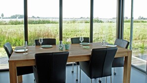 A dining table with chairs, set for four, overlooking a grassy field and water. - House Boat in Goengahuizen With Sauna (Goengahuizen)