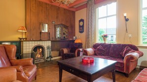 A cozy living room with a fireplace, leather furniture, a wooden ceiling, and a large window. - Secluded Farmhouse in Balkbrug with Hot Tub (Balkbrug)