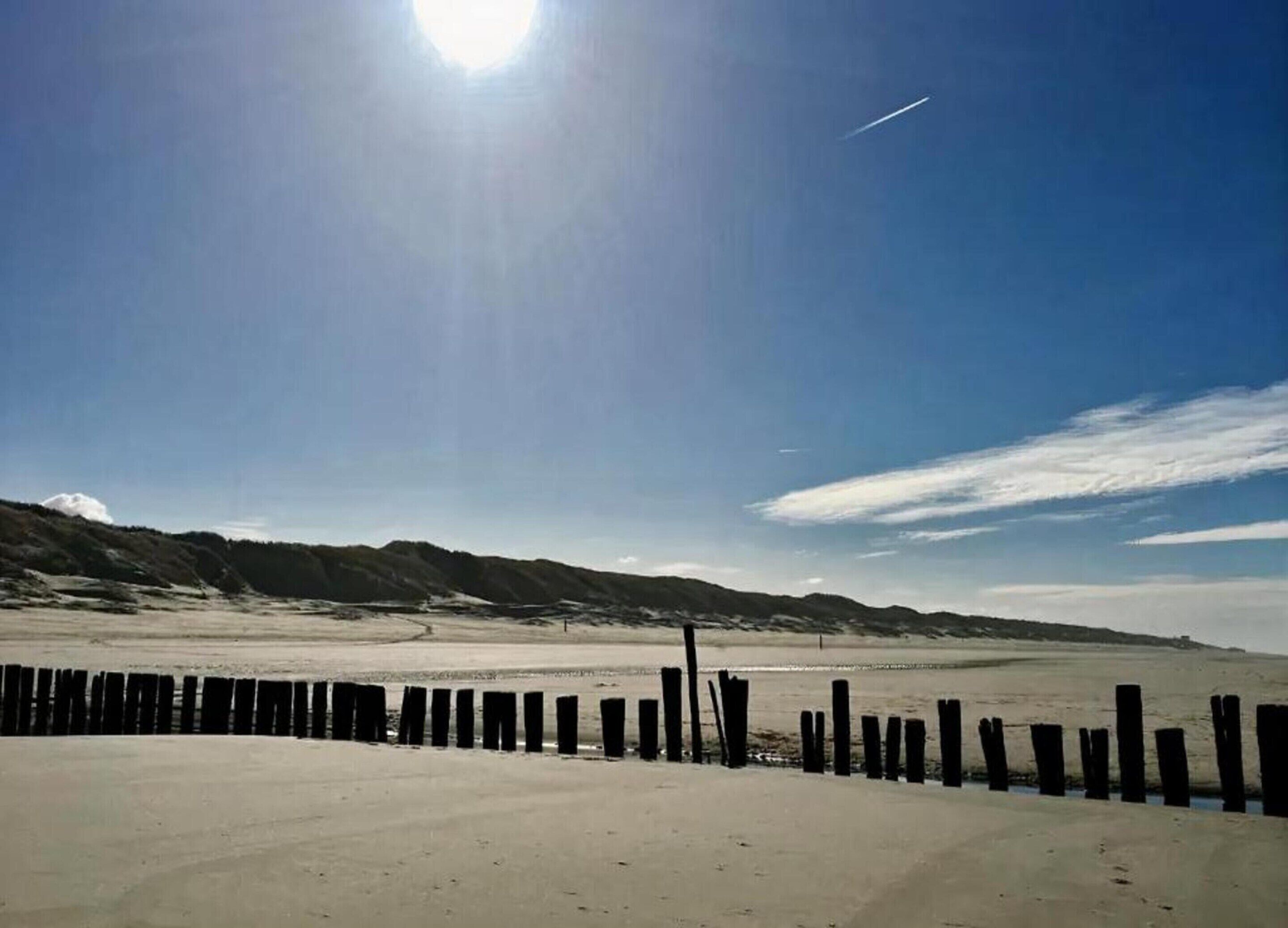 En strand med ett trästaket i förgrunden och en klar himmel.