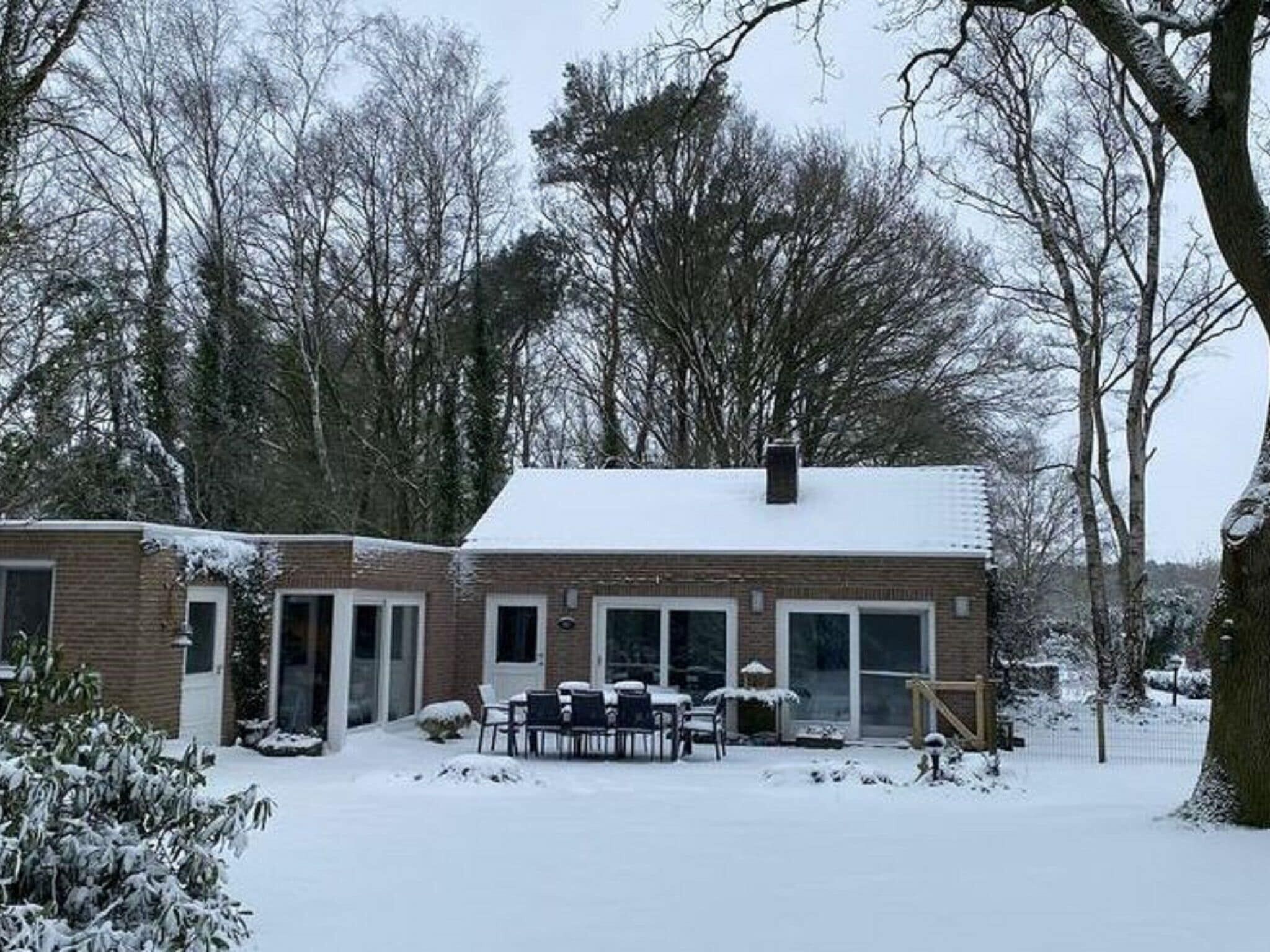 A two-story brick house with a covered patio and a snow-covered roof.