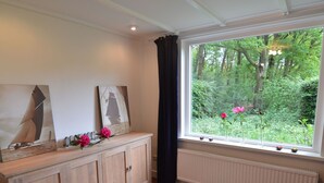A room with a wooden cabinet, a colorful striped rug, and a window with a view of greenery.