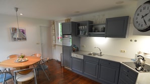 A kitchen with grey cabinets, a sink, a stove, and a dining area with a table and chairs.