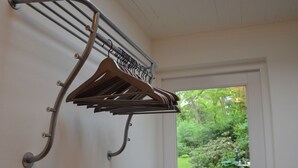 A wall-mounted drying rack with multiple hangers against a white door with a window.