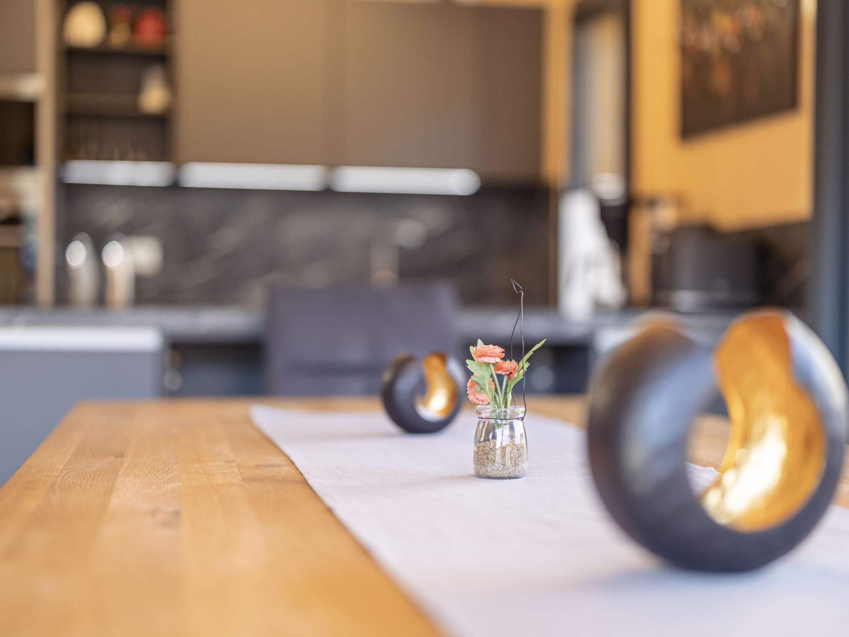Eine moderne Küche mit einem Holztisch, einer Vase mit Blumen und einem einzigartigen schwarzen und goldenen Stuhl.
