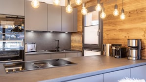 Una cocina moderna con horno empotrado, lavamanos y cafetera.