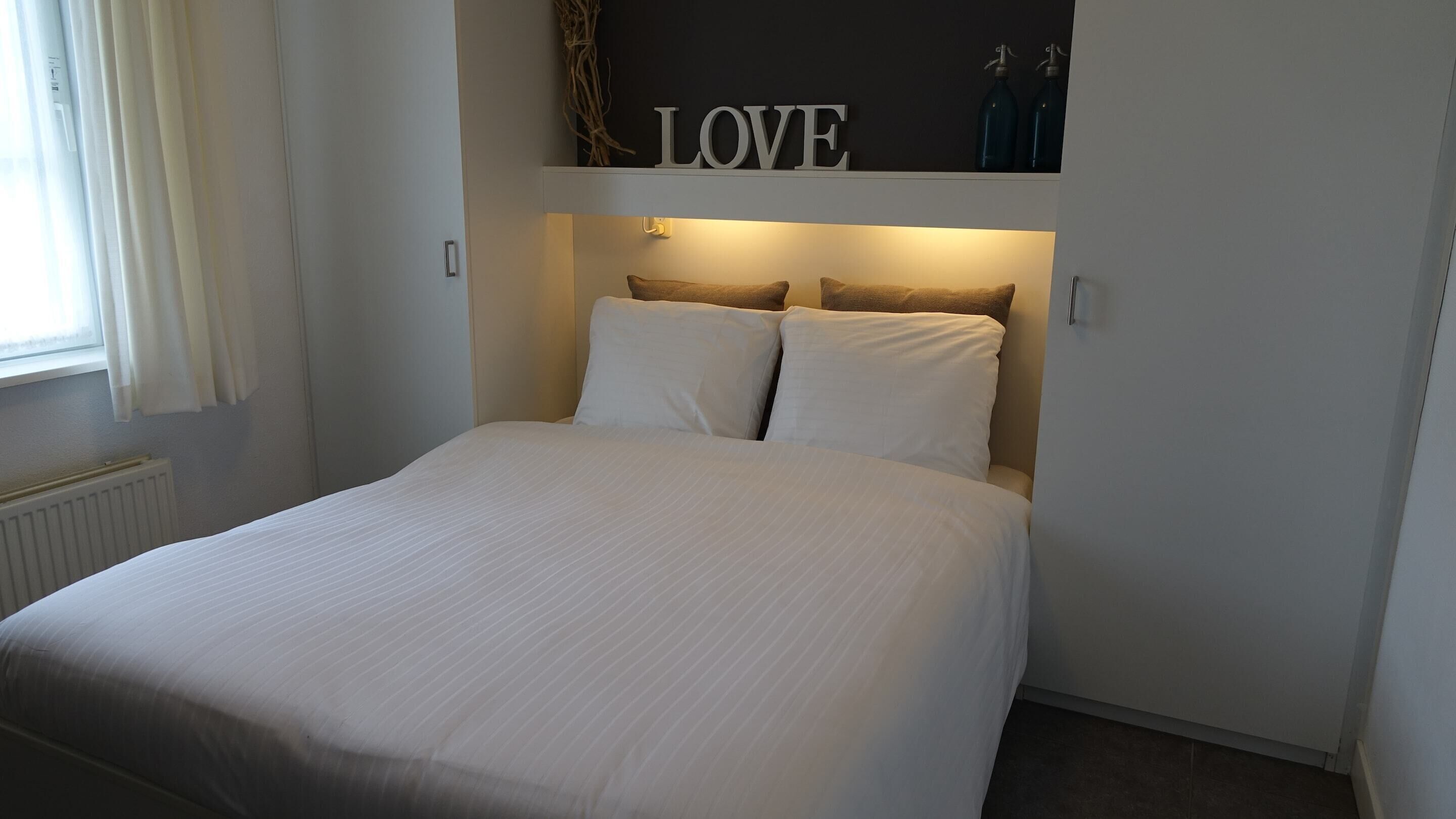 A bed with a headboard under a sign that reads 'LOVE.'