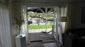 Una habitación con vista a un canal, una puerta de cristal, una planta en maceta y una lámpara.