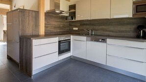 A modern kitchen with white cabinetry, a built-in oven, and a microwave.