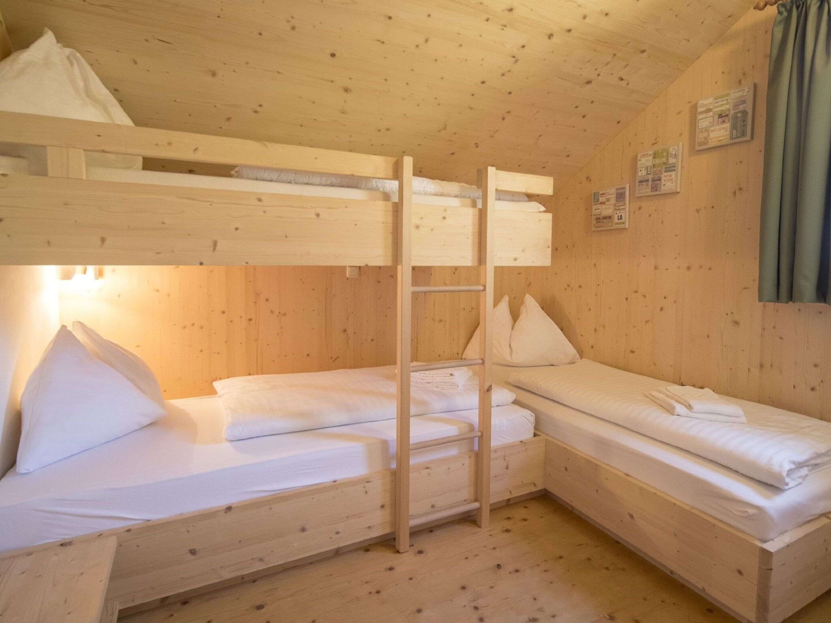 A wooden cabin with bunk beds, a ladder, and a small table.