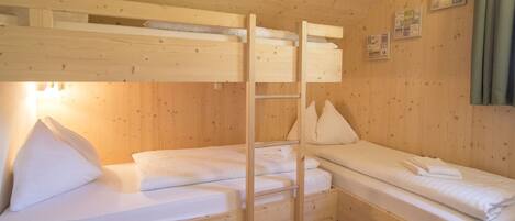A wooden cabin with bunk beds, a ladder, and a small table.