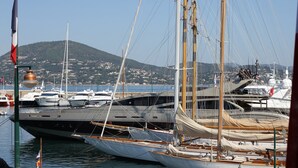 A marina with multiple yachts docked, a flagpole with a flag, and a mountainous backdrop. - Family-friendly Villa With Pool (Roquebrune-sur-Argens)