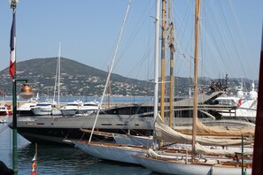A marina with multiple yachts docked, a flagpole with a flag, and a mountainous backdrop. - Family-friendly Villa With Pool (Roquebrune-sur-Argens)