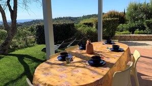 An outdoor dining area with a table set for four, surrounded by chairs, under a pergola with a view of the landscape. - Family-friendly Villa With Pool (Roquebrune-sur-Argens)