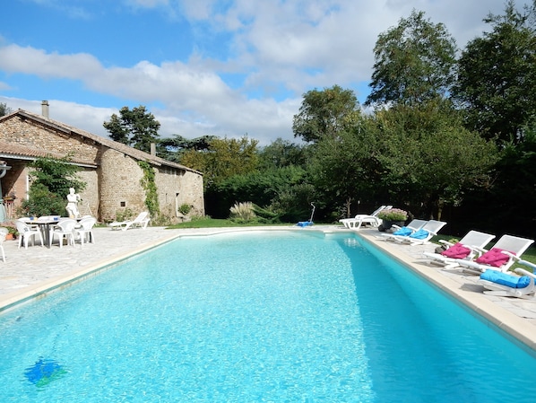Ein Pool mit Liegestühlen und einem Steinhaus.