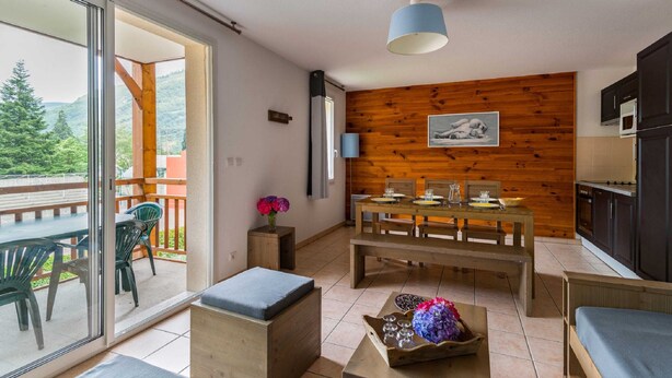 Een moderne woonkamer met een houten wand, een eettafel en een balkon met tuinmeubilair.